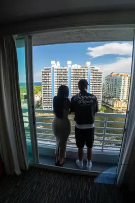 a man and a woman looking out of a window at Luxury Waterfront Condo Hilton Hotel Amenities Beach Pool Jacuzzi Jetskis Gym in Fort Lauderdale