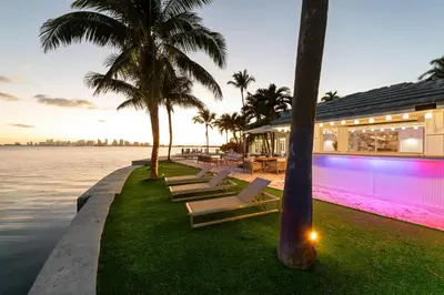 a house with a swimming pool next to the water at Villa Tropique in Miami Beach