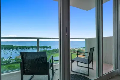 a balcony with two chairs and a view of a harbor at Modern Comfort Steps from the Ocean Breeze in Miami
