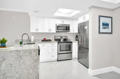 a kitchen with white cabinets and stainless steel appliances at Palm Oasis, Pool and Free Parking in Miami