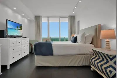 a bedroom with a large bed with a television and windows at Coastal Elegance and Luxury by the Water in Miami