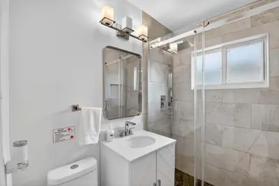 a white bathroom with a sink and a mirror at Victoria Park's Secret Estate in Fort Lauderdale