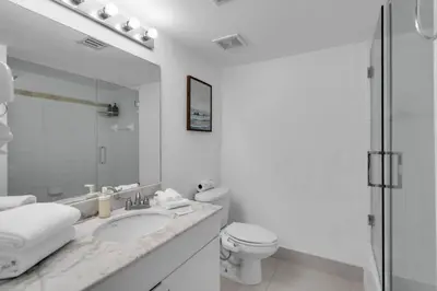 a white bathroom with a toilet and a sink at Stunning 2B2B Ocean and City Views with Free Parking in Miami