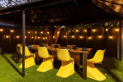 a wooden table and chairs with lights on the wall at 3BR Vibrant Havana Villa in Miami, Pool, Grill, Backyard in Miami