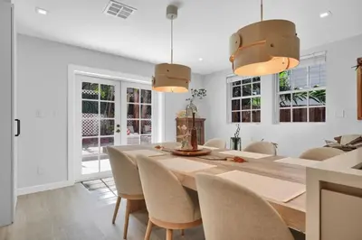 a white dining room with a wooden table and chairs at Home Away From Home in Coconut Grove in Miami