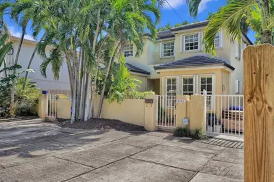 a house with palm trees in front of a fence at Home Away From Home in Coconut Grove in Miami