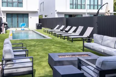 a backyard with lounge chairs and a pool and a fence at Parisian Vibe in Design District Miami with Private Pool BBQ Spacious Backyard in Miami
