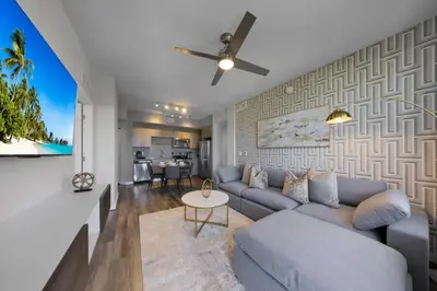 a living room with a blue couch and a ceiling fan at Casa Palmera in DTWN 3 Min From Las Olas in Fort Lauderdale