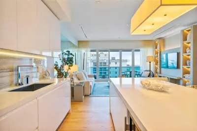a kitchen with white cabinets and a living room at Villa Royale Residences in Miami Beach