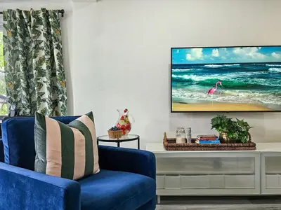 a living room with a blue chair and a tv on a wall at The Ruby - Hot Tub - King beds - Close to LMC in Fort Lauderdale