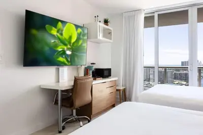 a hotel room with a desk and a bed and a window at 2BR 2BA at Beachwalk on 29 floor Full Equiped in Hallandale Beach