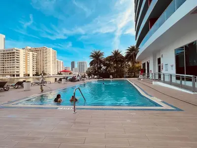 two people in a swimming pool in a building at 1 BR Full Kitchen- Pool Gym Beach 29th floor in Hallandale Beach