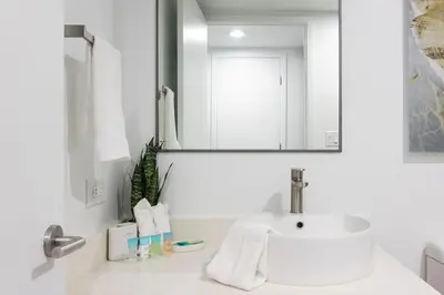 a white bathroom with a sink and a mirror at Family Beachwalk Studio- 29th floor in Hallandale Beach
