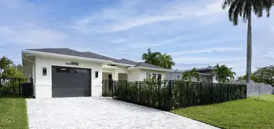 a white house with a black gate at New Villa Near Hardrock Fll Wboating Near Beach in Fort Lauderdale