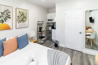 a bedroom with a white bed and a kitchen at Cozy Modern Studio Near Sunny Isles & Bal Harbour in North Miami