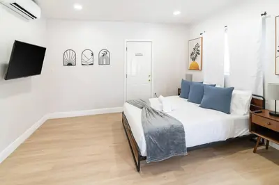 a white bedroom with a bed and a tv at Modern Studio Apt • Prime North Miami Location in North Miami
