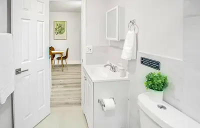 a white bathroom with a sink and a mirror at Spacious North Miami Studio | 2 Queen Beds in North Miami