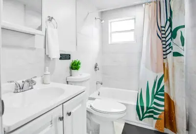 a white bathroom with a toilet and a sink at Spacious North Miami Studio | 2 Queen Beds in North Miami