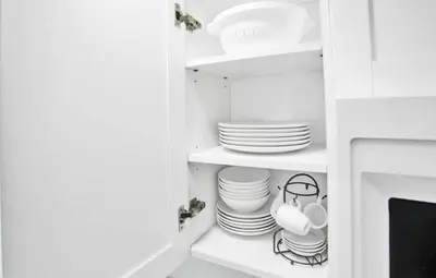 a white cabinet with plates and dishes in it at Spacious 1BR in North Miami | Near Beach & Dining in North Miami