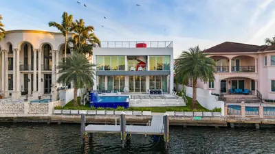a large house on the water with palm trees at Miami Modern Heated Pool and Dock in Sunny Isles Beach
