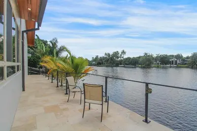 a row of chairs sitting next to a body of water at Vista Azul Lake Front Home with Hot Tub and Swim Spa, Fishing Dock, Gym, Game Room with Darts, Ping Pong, A Pool Table and more! in Miami Lakes