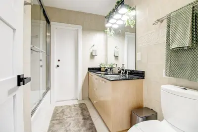a bathroom with a sink and a toilet and a mirror at Vista Azul Lake Front Home with Hot Tub and Swim Spa, Fishing Dock, Gym, Game Room with Darts, Ping Pong, A Pool Table and more! in Miami Lakes