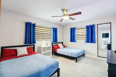 a bedroom with two beds and a ceiling fan at Vista Azul Lake Front Home with Hot Tub and Swim Spa, Fishing Dock, Gym, Game Room with Darts, Ping Pong, A Pool Table and more! in Miami Lakes