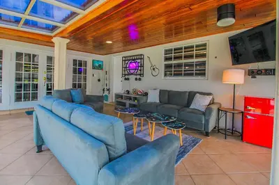 a living room with two blue couches and a tv at Vista Azul Lake Front Home with Hot Tub and Swim Spa, Fishing Dock, Gym, Game Room with Darts, Ping Pong, A Pool Table and more! in Miami Lakes