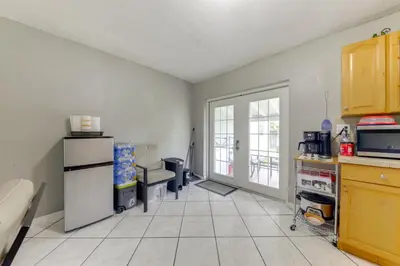 a kitchen with a refrigerator and a tiled floor at Fenced-In Yard Home 3 Mi to Hard Rock Stadium! in Miramar