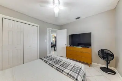 a bedroom with a tv and a door with a fan at Fenced-In Yard Home 3 Mi to Hard Rock Stadium! in Miramar