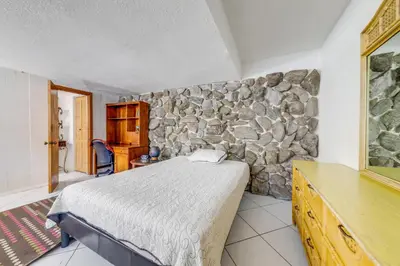a bedroom with a bed and a stone wall at 5 Mi to Hollywood Blvd! Miramar Apt with Shared Pool in Miramar