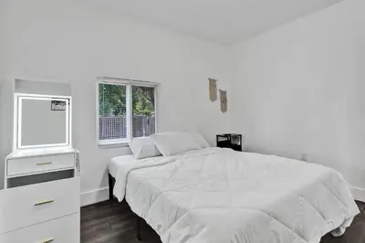 a white bedroom with a bed and a window at Miami Heart Retreat, Stylish & Central With Games in Miami
