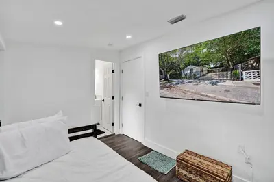 a white room with a bed and a tv on a wall at Miami Heart Retreat, Stylish & Central With Games in Miami