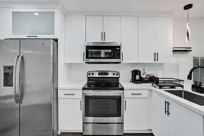 a kitchen with white cabinets and a stainless steel refrigerator at Miami Heart Retreat, Stylish & Central With Games in Miami