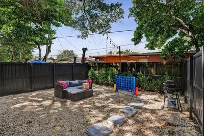a backyard with a couch and a fence at Heart of Miami Oasis, Modern, Steps from It All in Miami