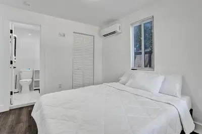a white bedroom with a bed and a toilet at Heart of Miami Oasis, Modern, Steps from It All in Miami