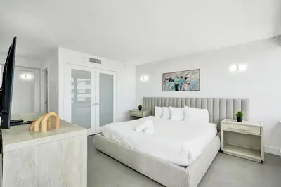 a white bedroom with a bed and a television at Oceanfront Luxury 3BR 3BA Condo with Resort Pools Gym and Sauna 902 in Miami Beach