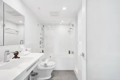 a white bathroom with a toilet and a sink at Oceanfront Luxury 3BR 3BA Condo with Resort Pools Gym and Sauna 902 in Miami Beach