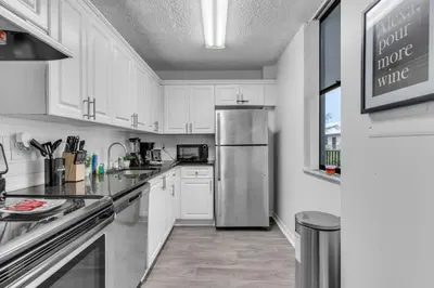 a kitchen with white cabinets and a stainless steel refrigerator at Urban Escape 2 Bed Unit In Miami near Whole Foods in North Miami