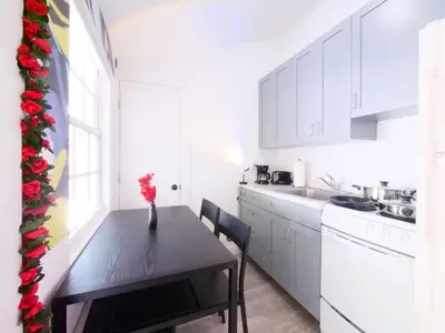 a kitchen with white cabinets and a table with a vase of flowers at Miami Wynwoods nook the graffiti stylish studio in Miami