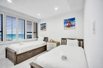 two beds in a room with white walls and windows at Steps to the Beach 3BR 2BA Condo Resort Perks and Ocean Glimpse 1406 in Miami Beach