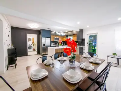 a dining room and kitchen with a wooden table and chairs at Dania Beach 3-bedroom house - Pool,Parking,Grill in Dania Beach