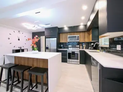 a kitchen with a counter with stools and a clock on the wall at Dania Beach 3-bedroom house - Pool,Parking,Grill in Dania Beach