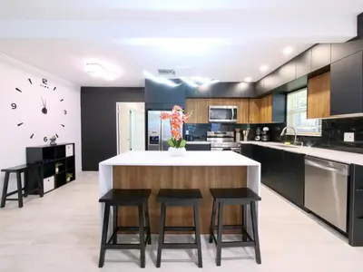 a kitchen with a large island with chairs and a counter at Dania Beach 3-bedroom house - Pool,Parking,Grill in Dania Beach