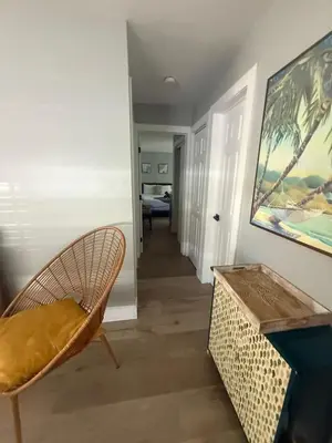 a hallway with a chair and a table and a painting at 2 Beach Units for 6 | Patio + Free Parking in Dania Beach
