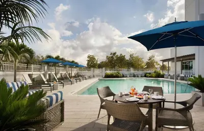 a patio with a table and chairs next to a pool at Hilton Garden Inn Miami Dolphin Mall in Miami