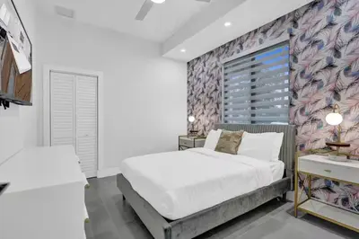 a bedroom with a large white bed and a wall at New Construction Villa HotTub Heated Pool Gameroom in Fort Lauderdale