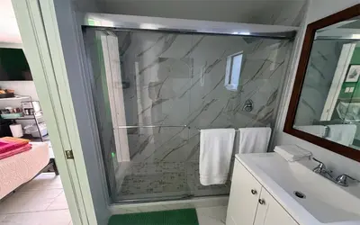 a bathroom with a glass shower and a sink at Garden of Manors - Men Only Clothing Optional Boutique Guesthouse in Florida in Fort Lauderdale