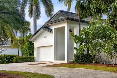 a white house with a garage and palm trees at Villa Asher - Waterfront with dock in Miami