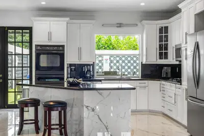 a kitchen with white cabinets and a large island with stools at Villa Asher - Waterfront with dock in Miami